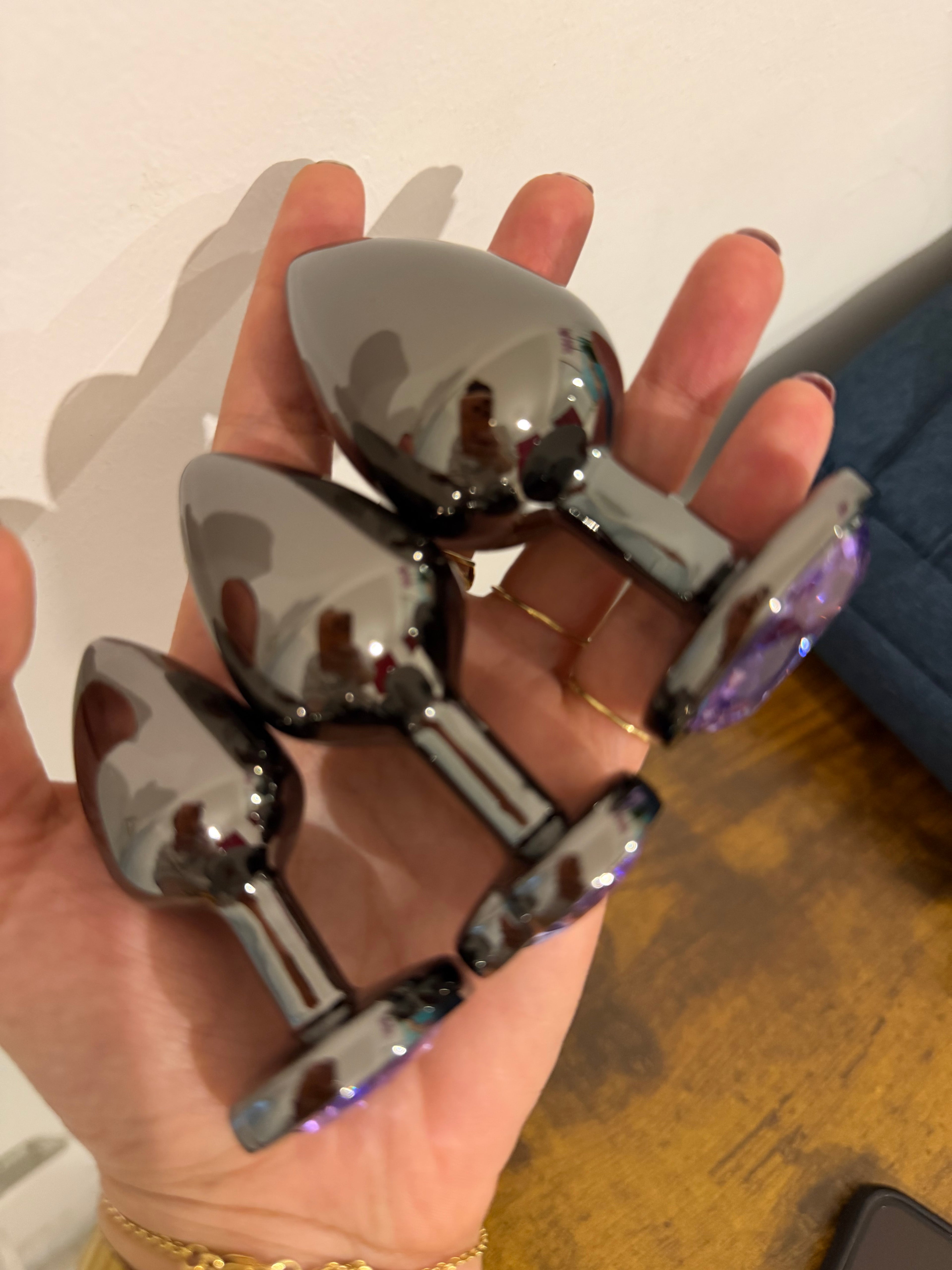 Set of metal anal plugs with jeweled base held in hand luxury adult toy